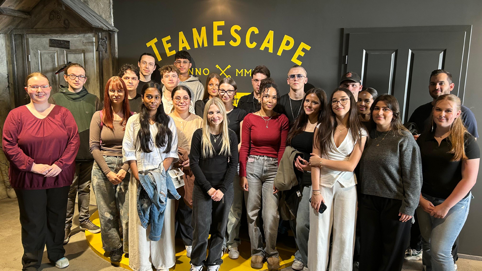 Junge Menschen stehen aufgereiht als Gruppe vor einer Wand mit dem Schriftzug "TeamEscape". (Quelle: BAMF) Junge Menschen stehen aufgereiht als Gruppe vor einer Wand mit dem Schriftzug "TeamEscape".