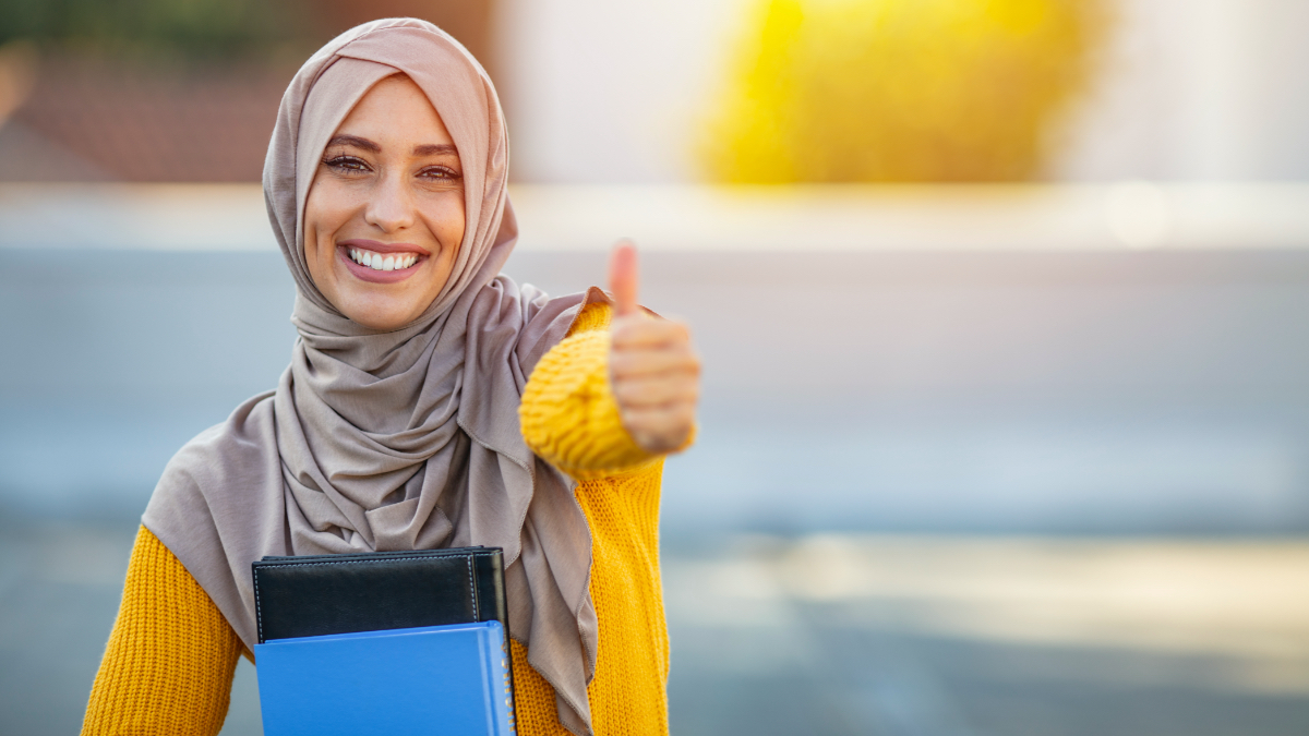 A young woman wearing a headscarf holds two books in one of her hands. (Source: istock | dragana991) A young woman wearing a headscarf holds two books in one of her hands.